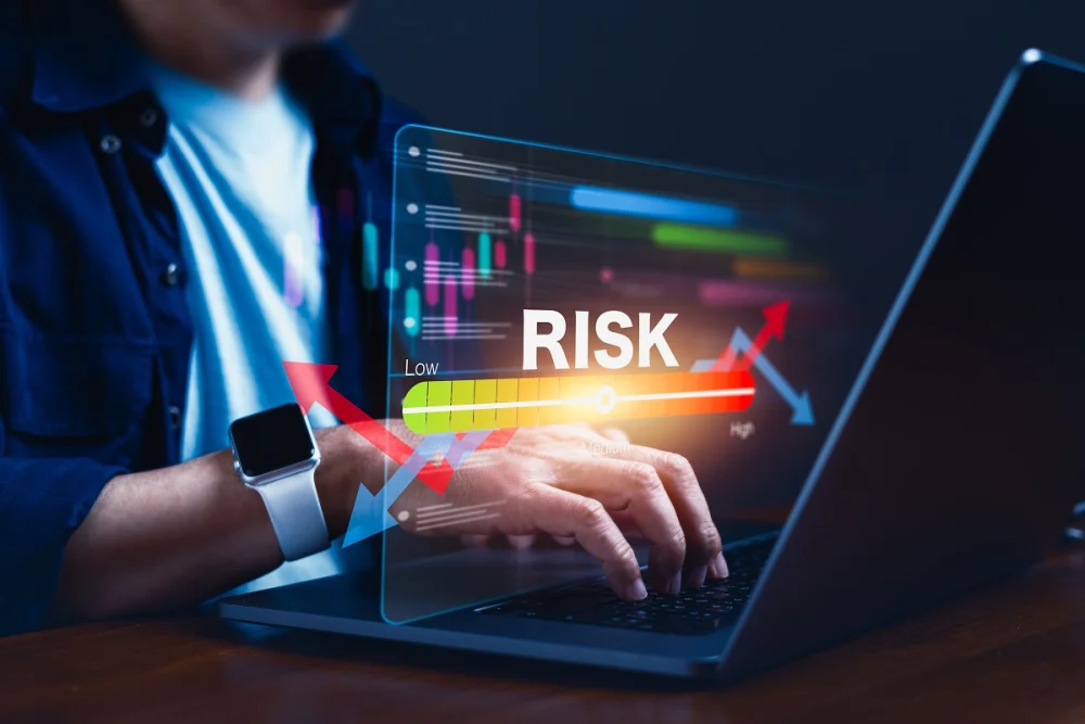 A person typing on a laptop with a digital “risk level” gauge displayed across the screen, illustrating how KYC risk scores help evaluate customer risk from low to high