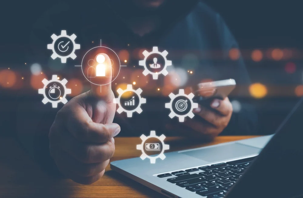 Compliance analyst using a mobile device and laptop to evaluate customer identity and risk indicators, representing KYC best practices such as risk-based verification and customer screening