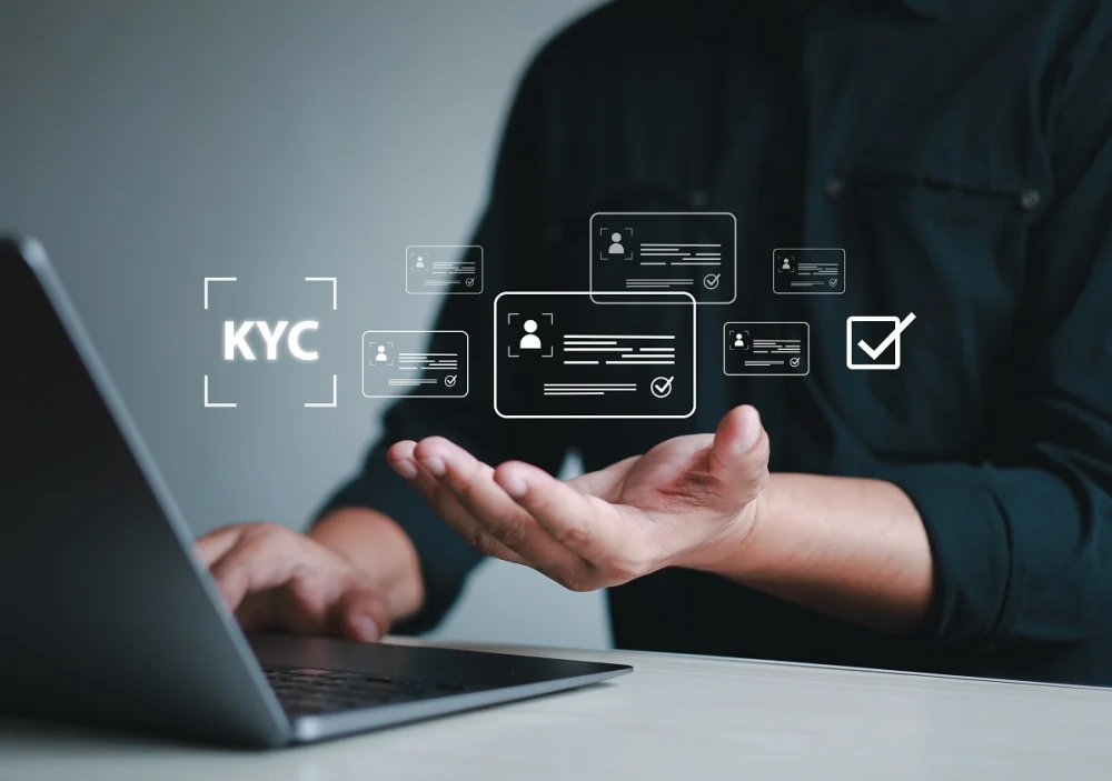 Person working on a laptop surrounded by digital KYC profile icons, symbolizing the complexity of managing customer data, reducing false positives, and maintaining consistent KYC workflows